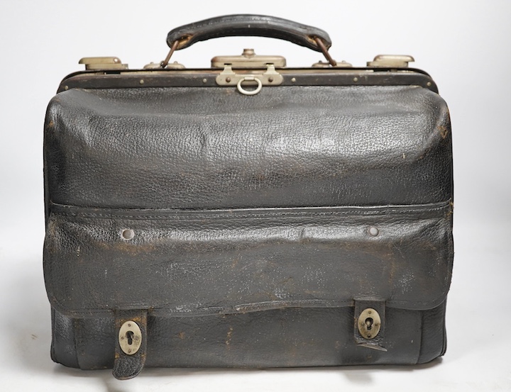 An Edwardian leather portmanteau case containing silver topped glass jars, the silver mm. TL, London 1904, case 36.5cm wide. Condition - fair